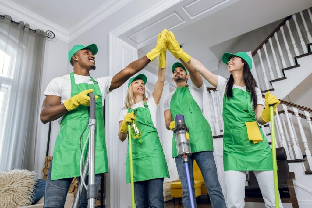 a happy faces of multiracial cleaners giving high five after cleaning